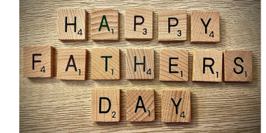 Scrabble tiles spell out 'Happy Fathers Day' on a wooden surface.