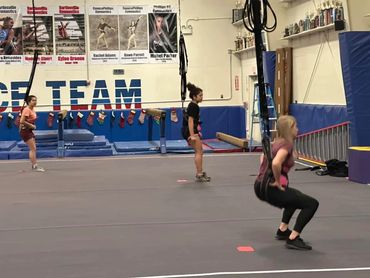 Two girls in pink and a girl in black exercising together