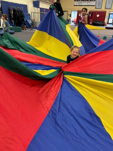 a little girl stuck into the huge colorful fabric
