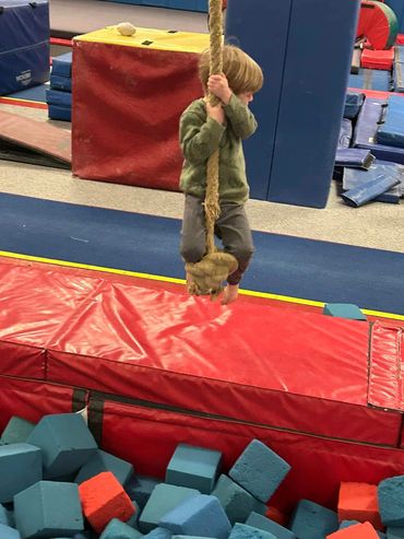 a little boy holding a rope and climbing