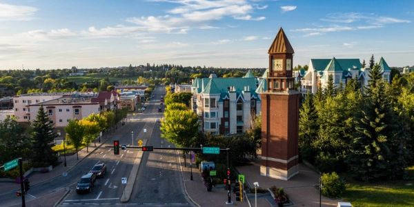 A small town street with a clock tower and green trees.
