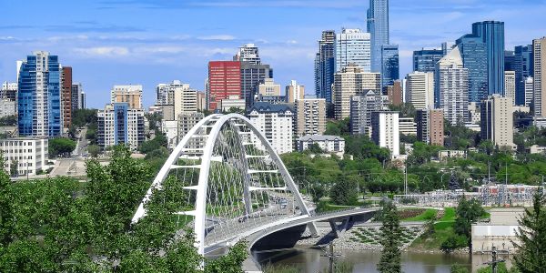 City skyline with a white arch bridge and greenery.