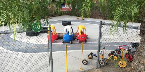Children's play area with toy cars and tricycles on a mini road track.