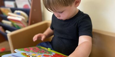A young boy intently reading a colorful children's book.