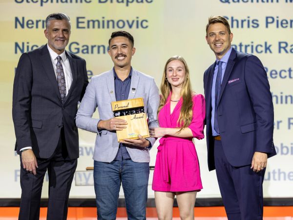 Four people posing with a personal cheer award.