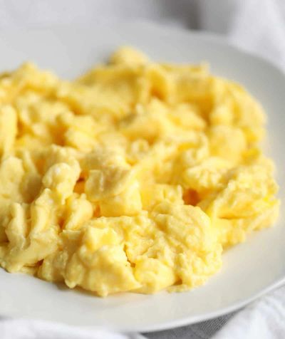 Creamy scrambled eggs served on a white plate.