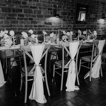 Elegant dining setup with wooden chairs and soft fabric decorations.
