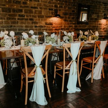 Elegant dining setup with wooden chairs and soft fabric decorations.