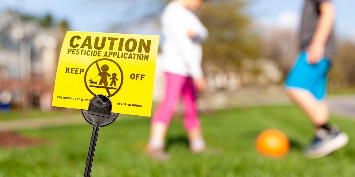 Kids playing next to yellow pesticide sign
