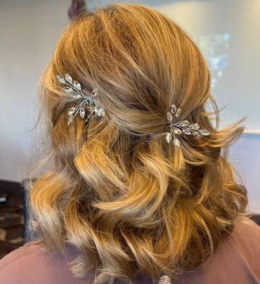 Curly blonde hair styled with elegant crystal hairpins.