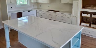 White perimeter kitchen cabinets and blue island cabinets with white and gray quartz countertops