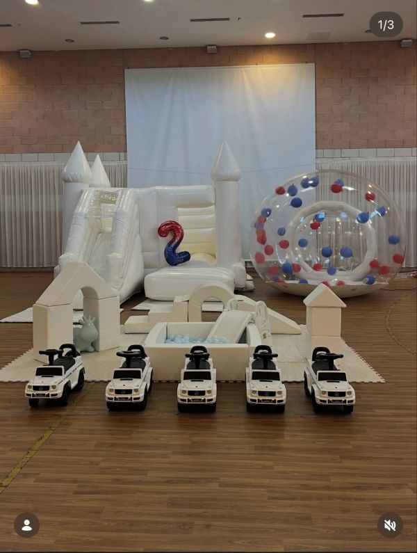 A white-themed indoor play area with toy cars and inflatable structures for a child's party.