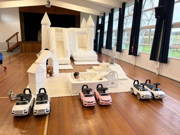 Indoor play area with toy cars and a white inflatable castle for children.