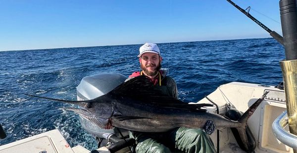 Eagle Eye Fishing Charters Captain Andrew holding his large sailfish caught in open ocean.