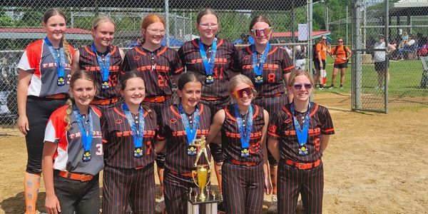 Girls' softball team posing with trophy and medals.