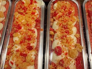 Two trays of deviled eggs topped with crumbled bacon and spices.