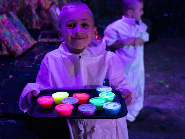 boy carrying a tray of glow in the dark paint 