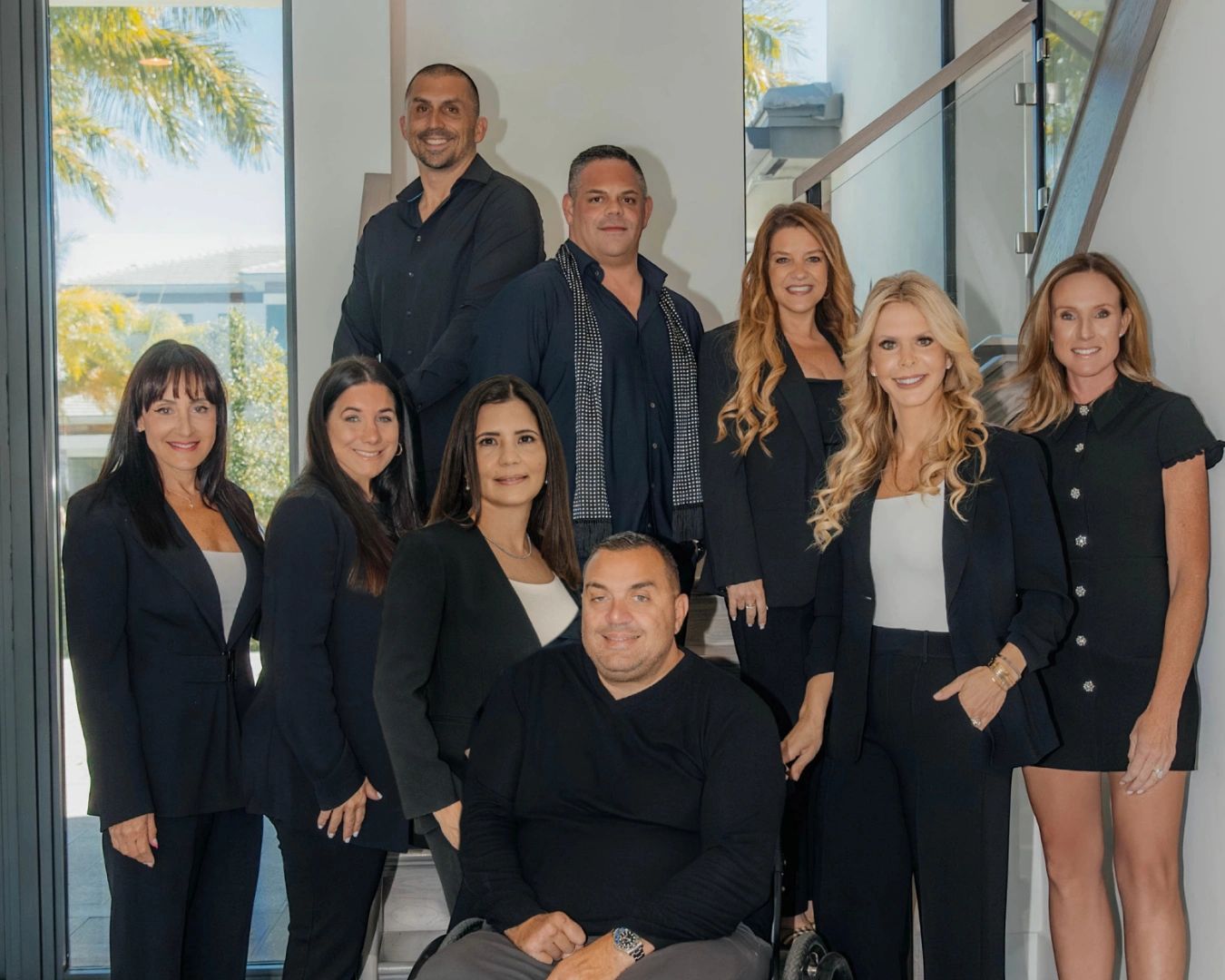 Group of professionals posing indoors with smiles and formal attire.