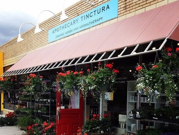 A storefront with a red door and hanging flower baskets.