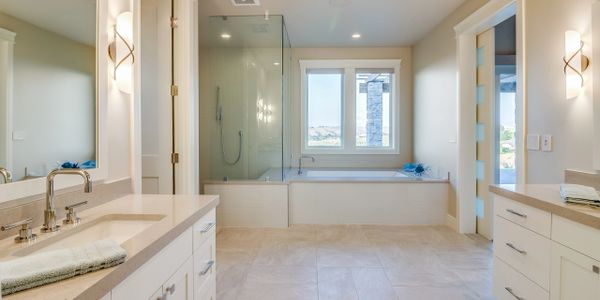 Master bathroom with glass shower and soaking tub. Tile floors and modern lighting.