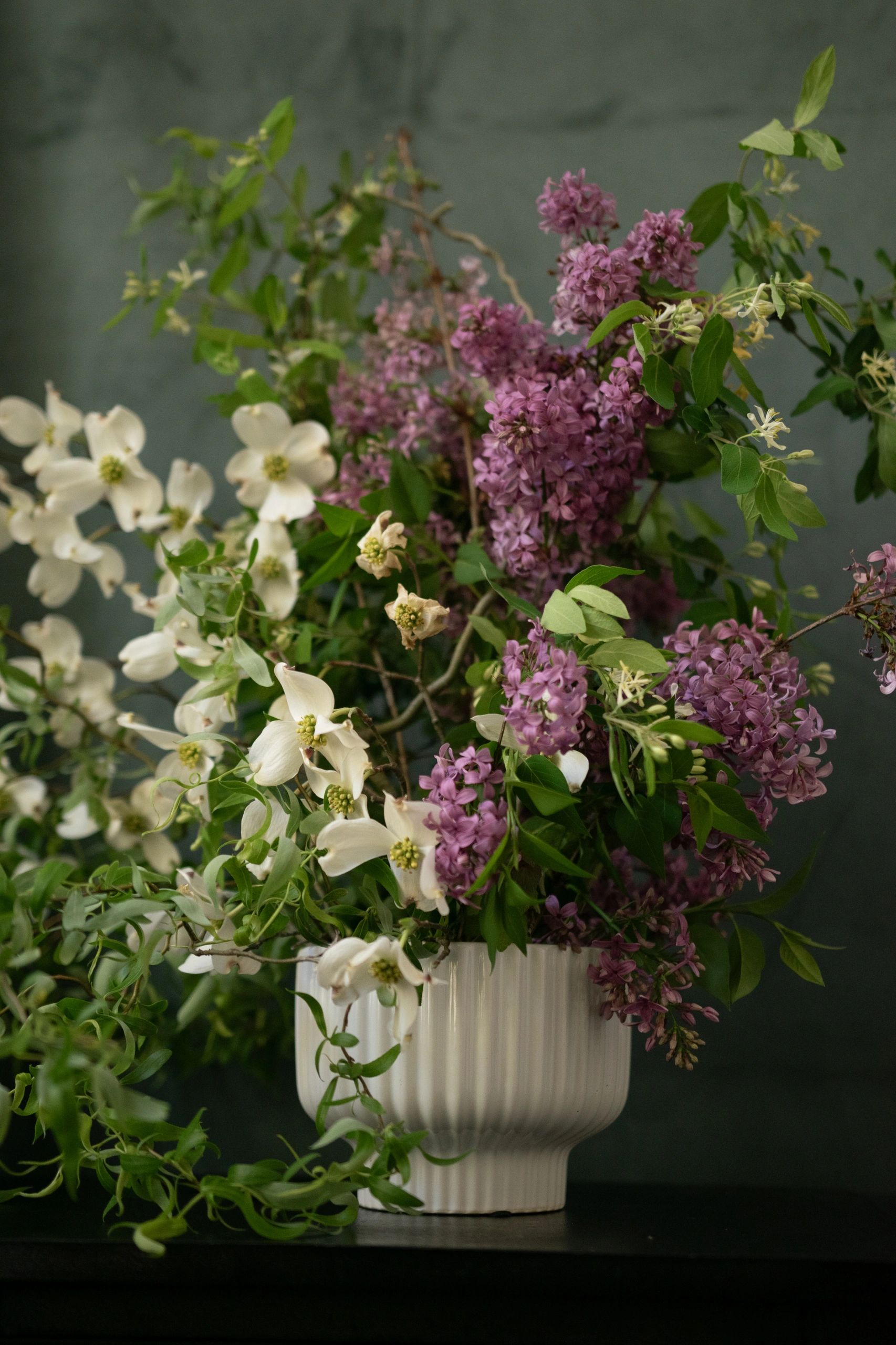 Elegant arrangement of white and purple flowers in a white vase.