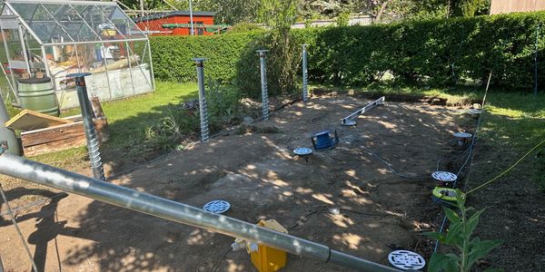 Metal screw piles installed in a garden for foundation support.