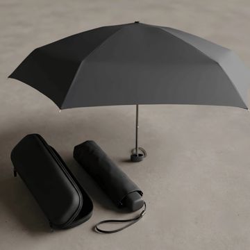 Paraguas negro desplegado con funda y estuche a su lado.
