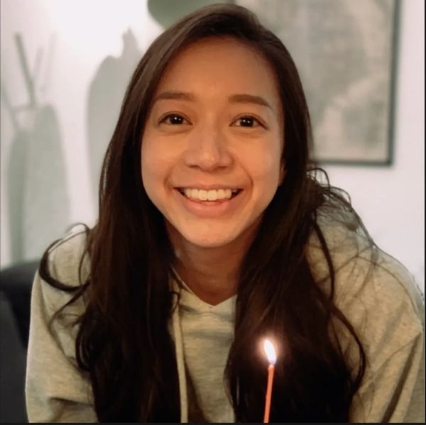 Ms. Jane Au smiling, holding a candle, and wearing a hoodie