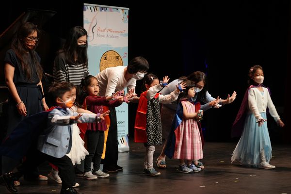 A group of kids bowing on stage in a reply of crowd appreciation