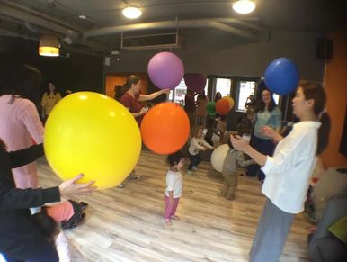 A group of people, including adults and children, engaged in an activity involving  colorful balloon