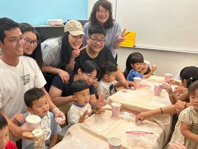 A group of adults and children gathered around tables, likely participating in an activity together