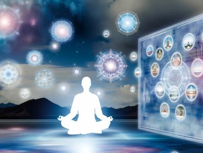 A person sitting in lotus position with orbs of lights floating and a computer screen to the right.