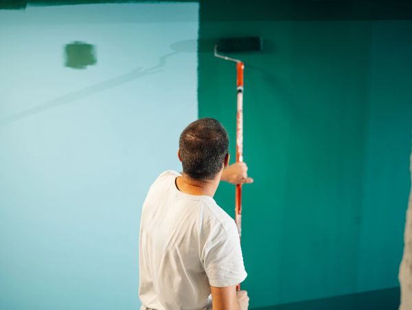 Painter applying green paint on wall with roller