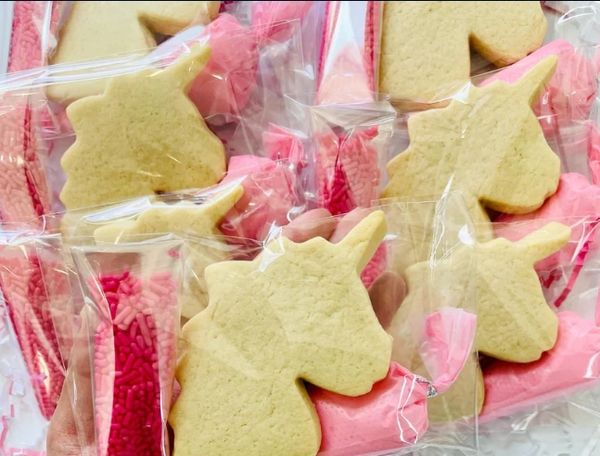 Unicorn-shaped cookies packaged with pink decorations.
