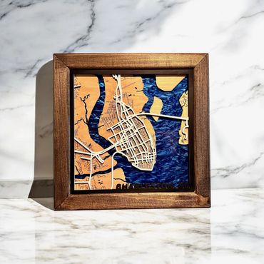 Framed wooden map art of Charleston, SC with blue water details.