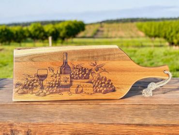 Wooden serving board with wine and grape design outdoors.