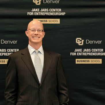 Man in suit standing in front of entrepreneurship center backdrop.