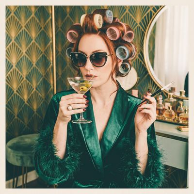 Woman with hair curlers holding a martini and cigarette.
