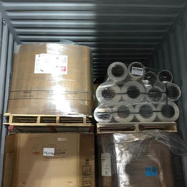 Stacked pallets with wrapped goods inside a metal container.