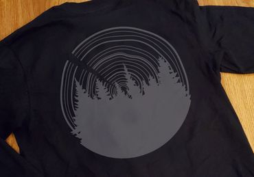 Tree line with a tree ring pattern in the sky. Placed on a long sleeve shirt as a mock-up design.