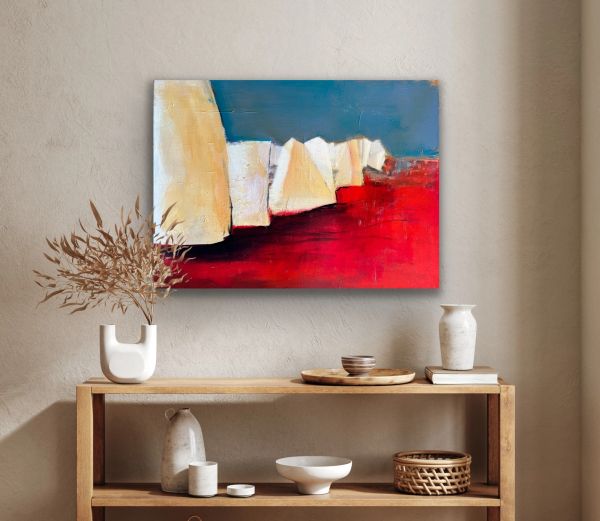 Abstract painting with bold red, blue, and cream colors above a wooden shelf.