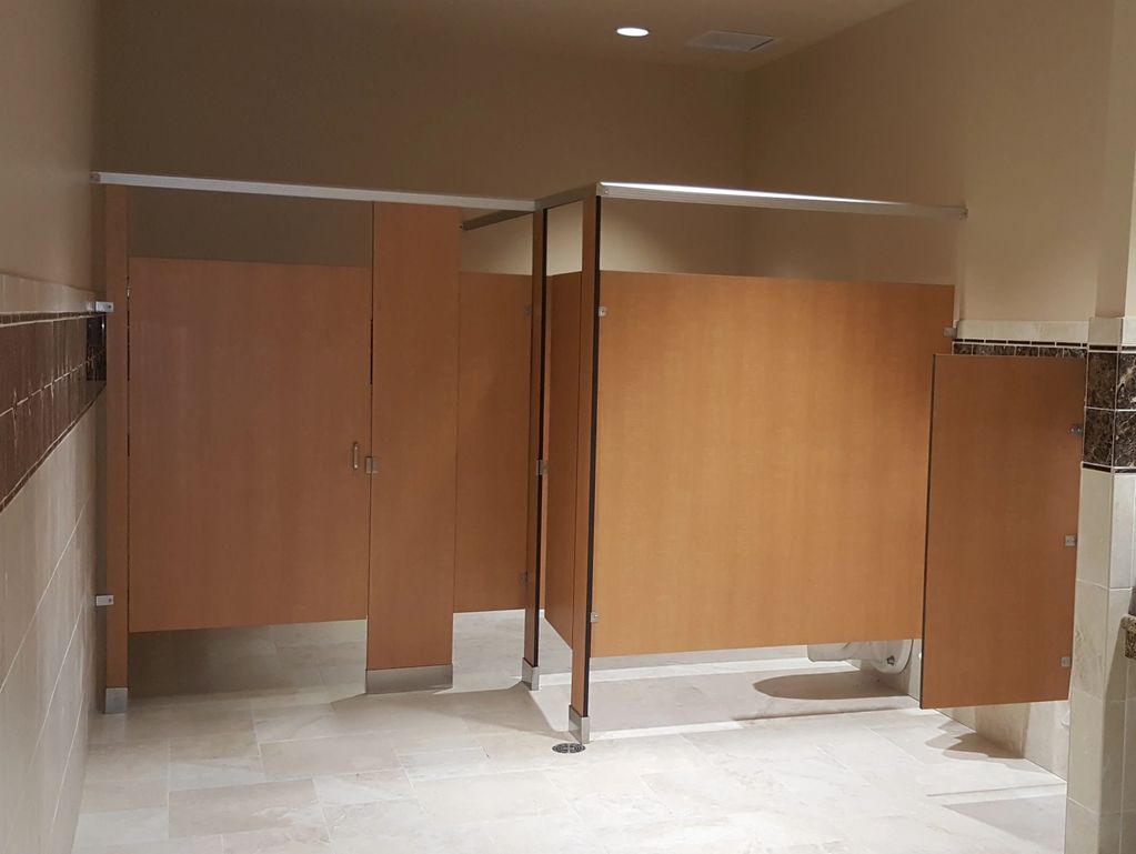 Floor mounted and overhead braces solid phenolic partitions in a public restroom.