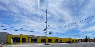 Wide view of a yellow building under a partly cloudy sky.