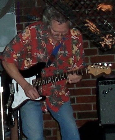 Man passionately playing electric guitar in a casual live music setting.