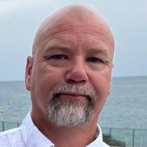 Portrait of a bald man with a gray beard near the sea.