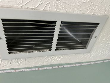 White ceiling vent with bent slats and textured ceiling.