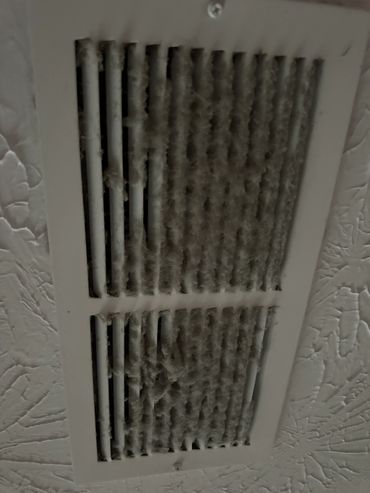 Dust-covered air vent on a ceiling needing cleaning.