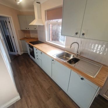 Modern galley kitchen with light wood countertops and blue cabinets.
