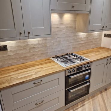 Modern kitchen with wooden countertop and white cabinetry.
