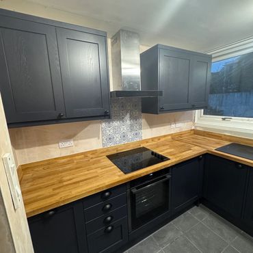 Modern kitchen with dark cabinets and wooden countertops.
